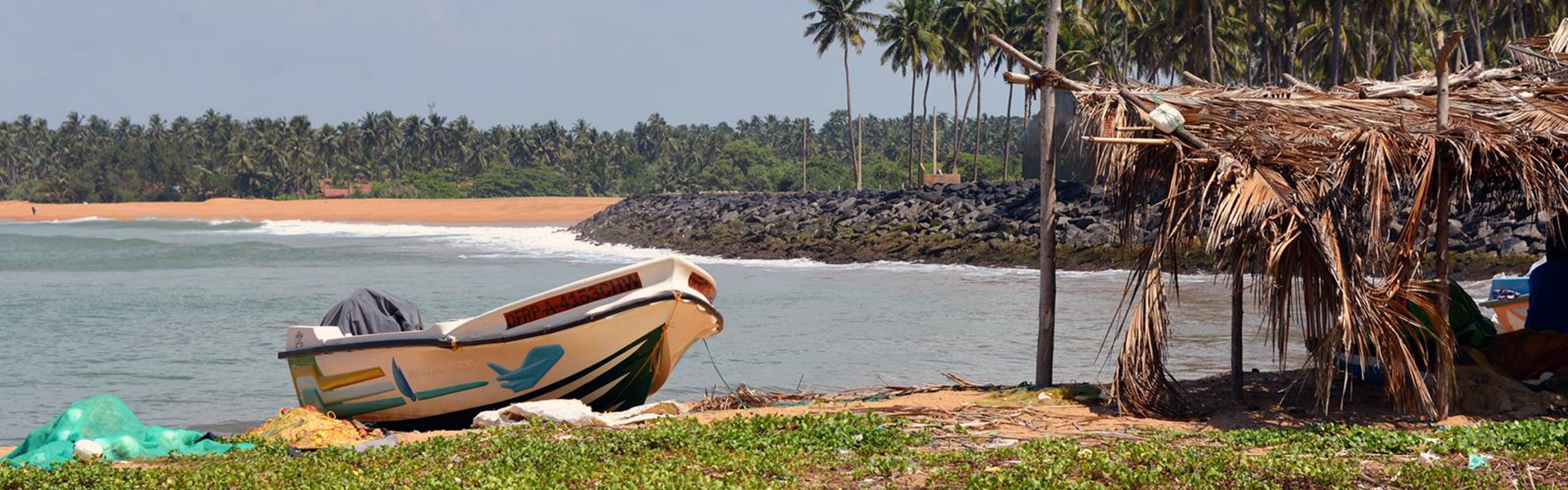 Fischerboot an der Küste Sri Lankas neben einer einfachen Palmenhütte