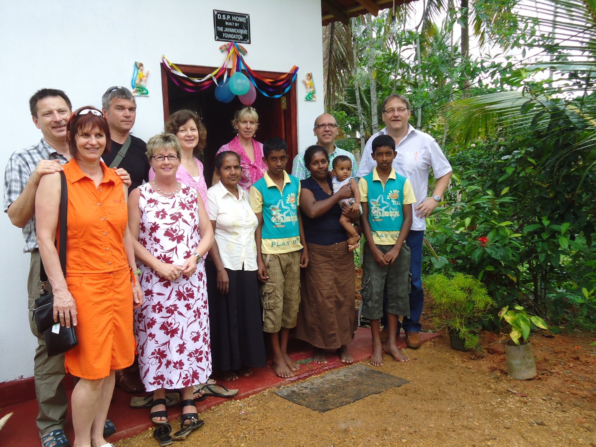 Vereinsmitglieder und Menschen vor Ort gemeinsam vor einem D.S.P.-Haus in Sri Lanka
